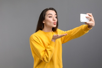 Photo of Attractive young woman taking selfie with phone on color background