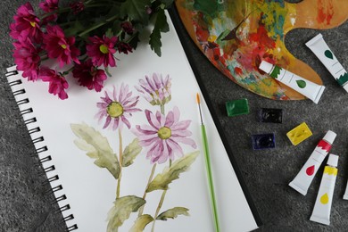 Flat lay composition with beautiful drawing of chrysanthemum flowers in sketchbook on grey table