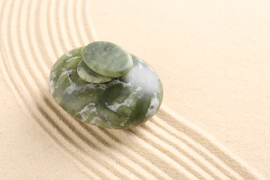 Photo of Zen garden stones on beige sand with pattern. Space for text