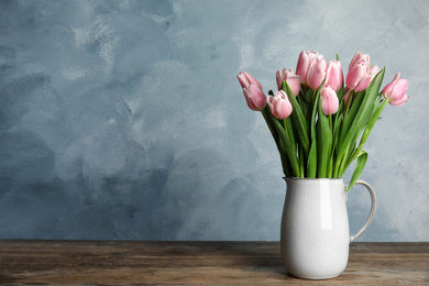 Beautiful pink spring tulips in vase on wooden table. Space for text