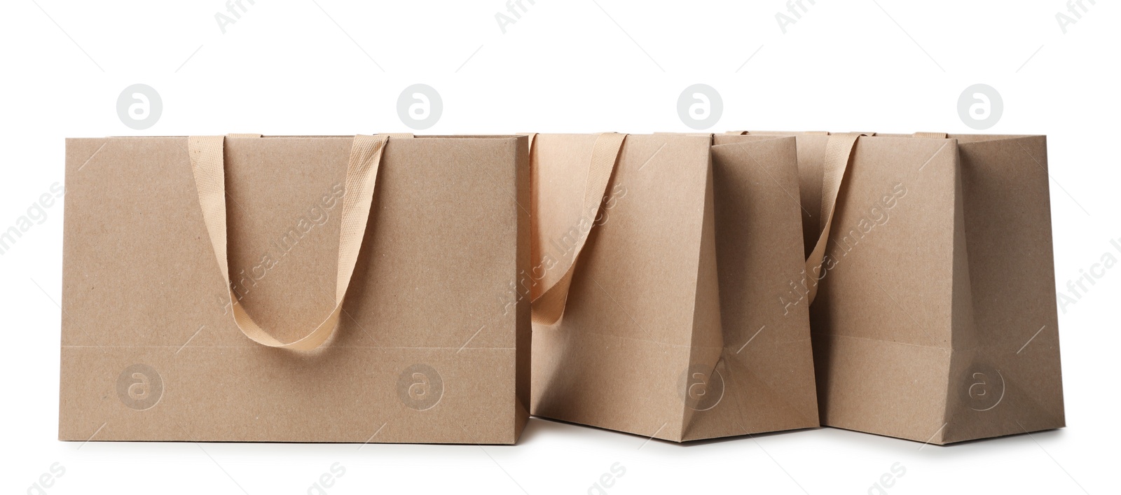 Photo of Paper shopping bags with comfortable handles on white background. Mockup for design