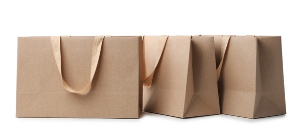 Photo of Paper shopping bags with comfortable handles on white background. Mockup for design