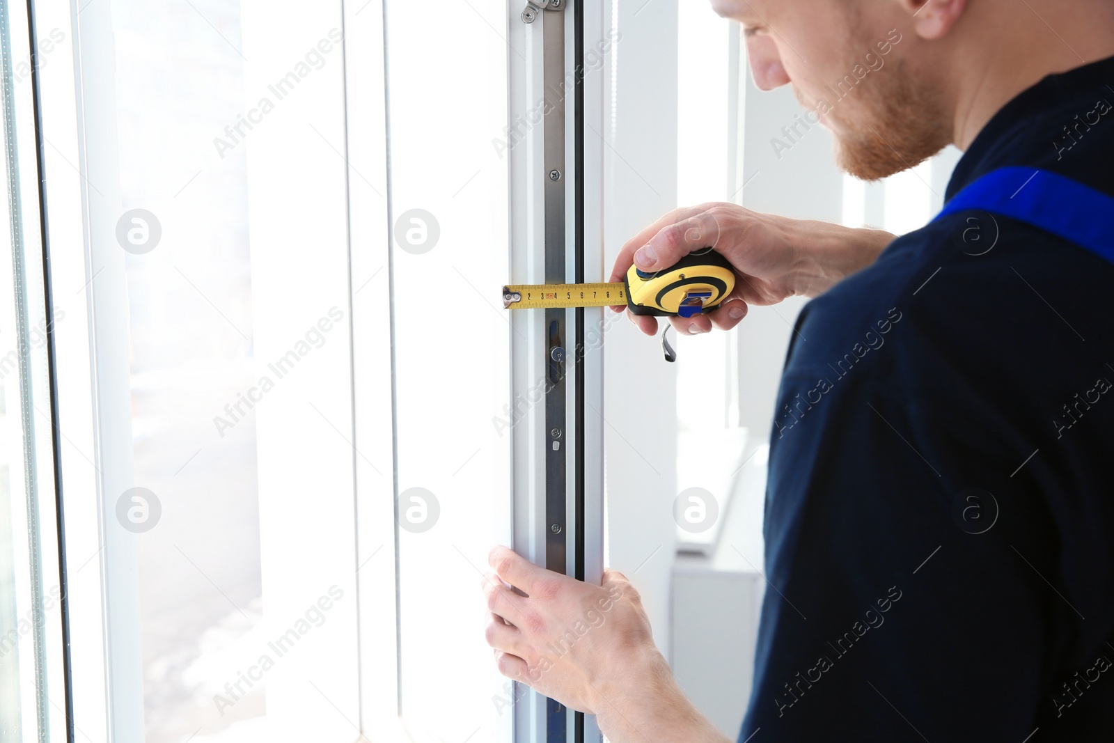 Photo of Service man measuring window for installation indoors, closeup