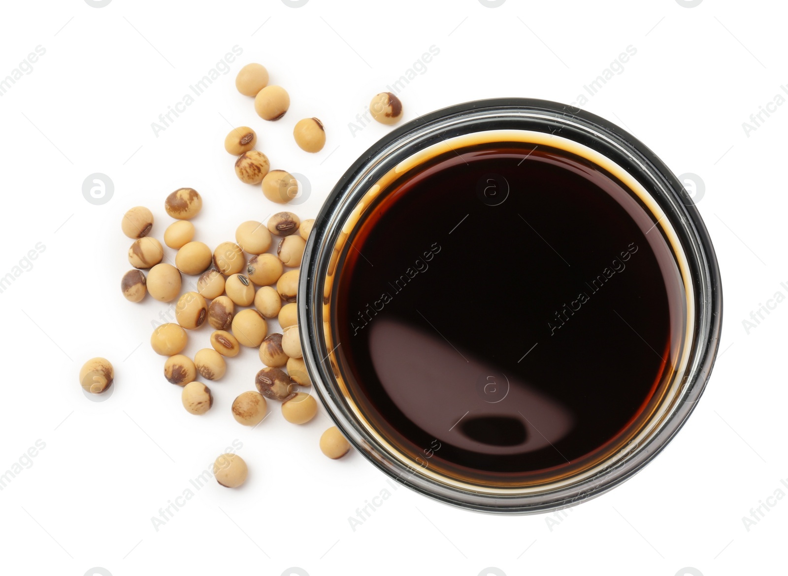 Photo of Tasty soy sauce in bowl and soybeans isolated on white, top view