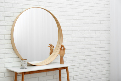 Round mirror on white brick wall in room. Space for text