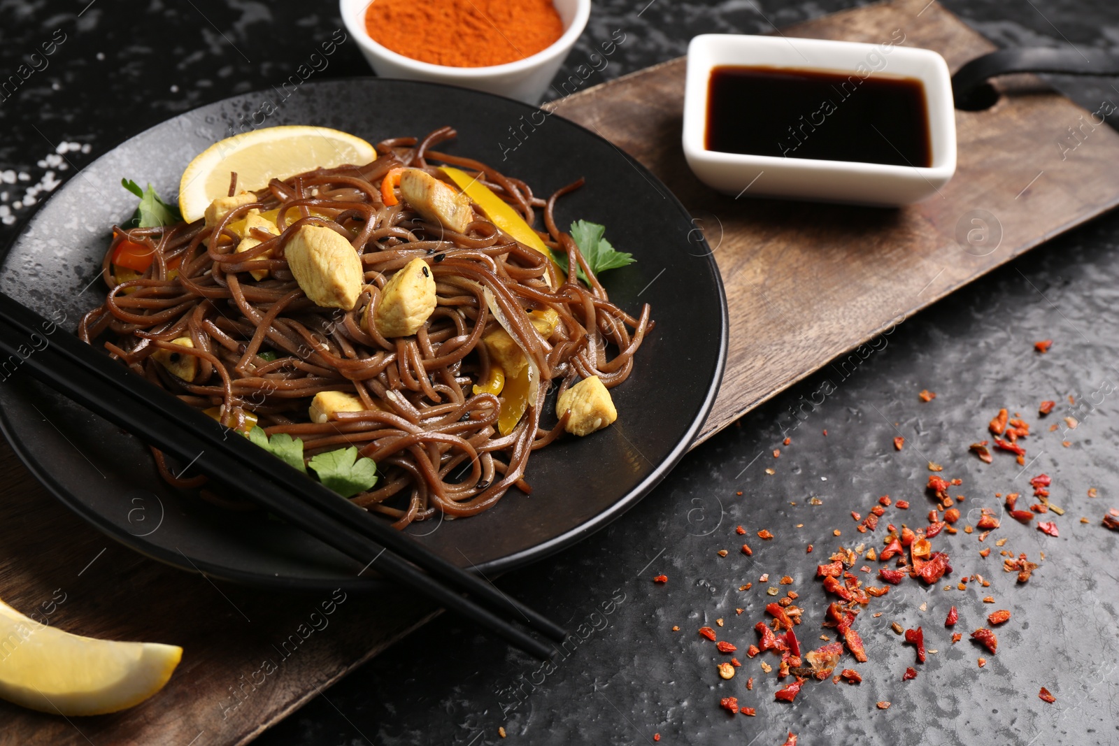 Photo of Stir-fry. Tasty noodles with vegetables and meat served on dark textured table