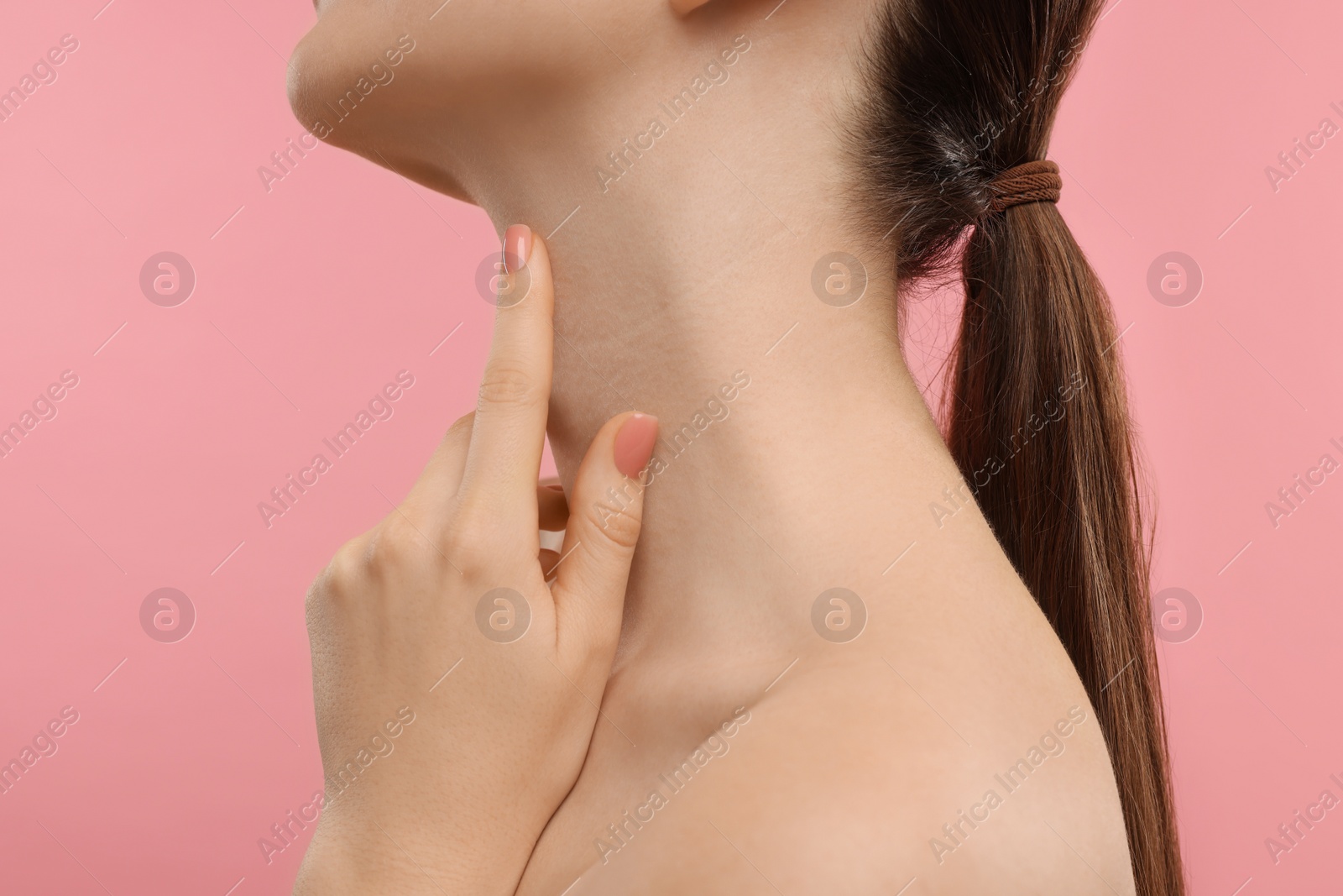 Photo of Woman touching her neck on pink background, closeup