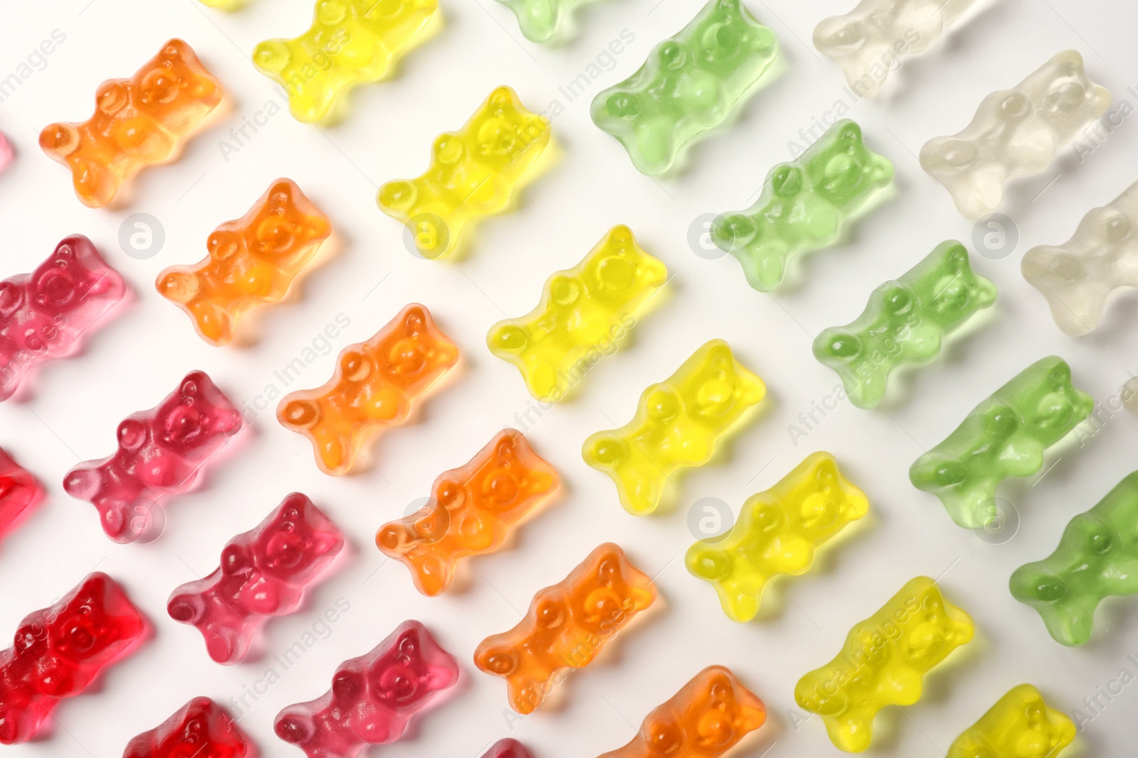 Photo of Many delicious little jelly bears on white background, top view