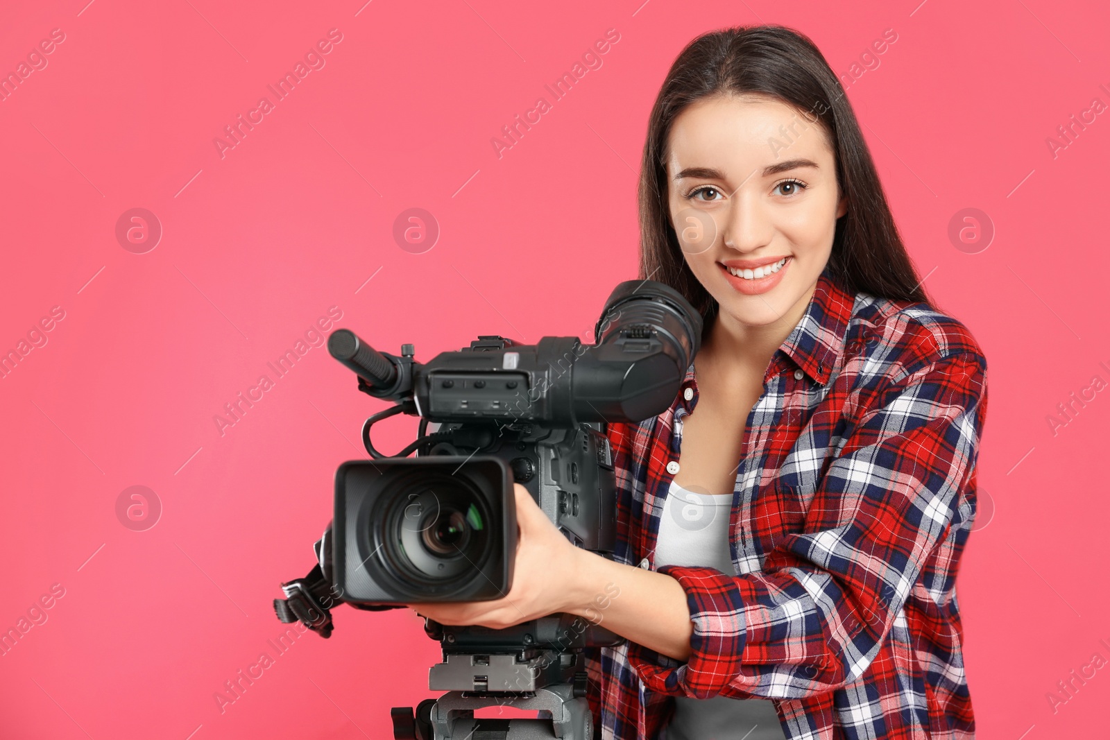 Photo of Operator with professional video camera on pink background