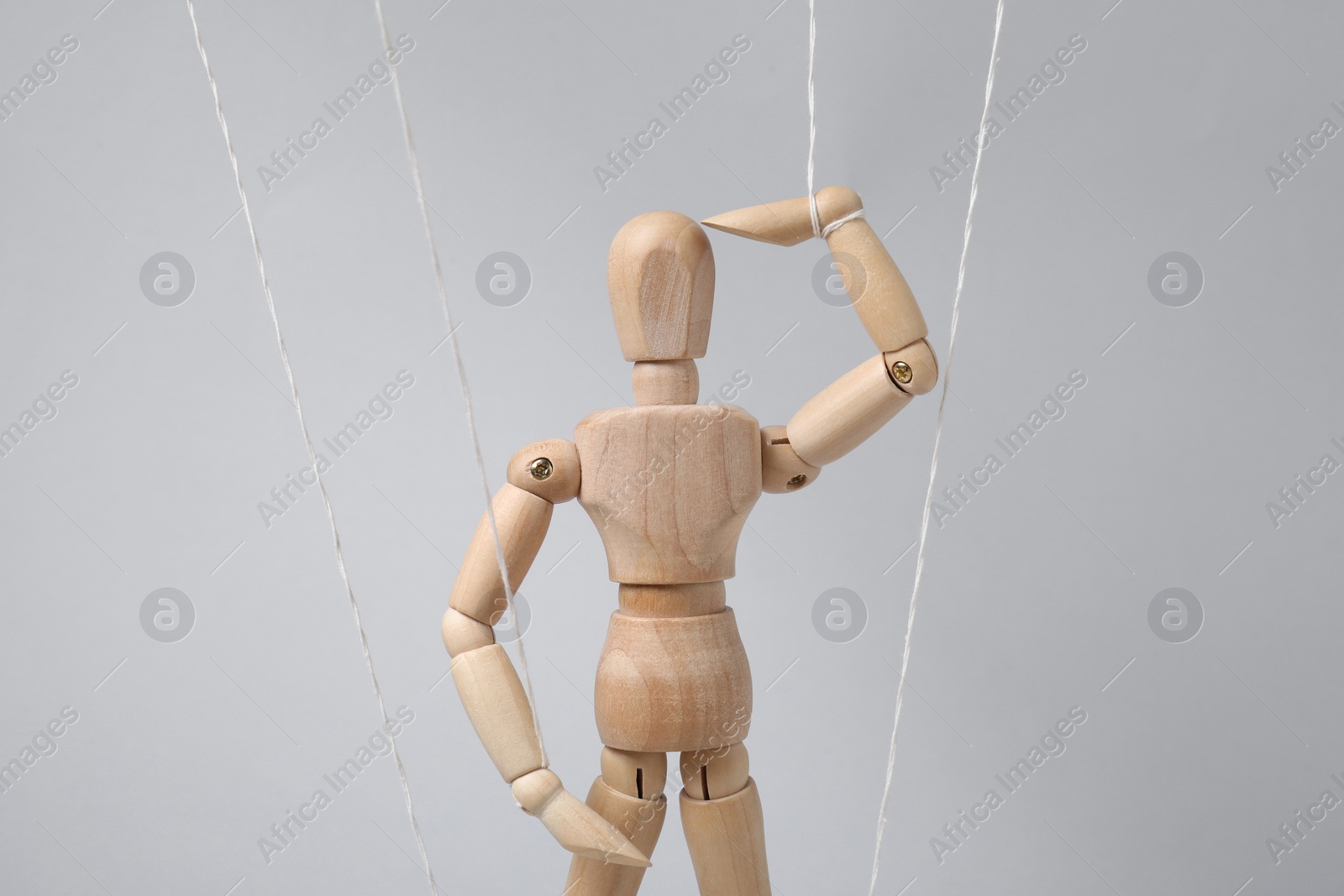 Photo of One wooden puppet with strings on light grey background