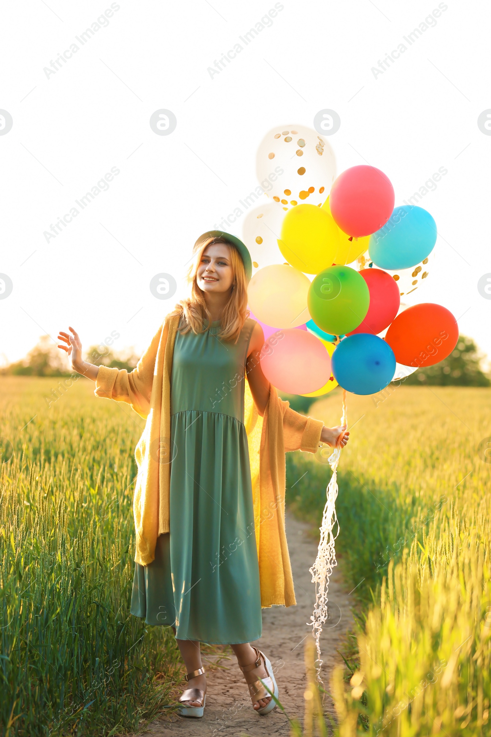 Photo of Young woman with colorful balloons in field on sunny day