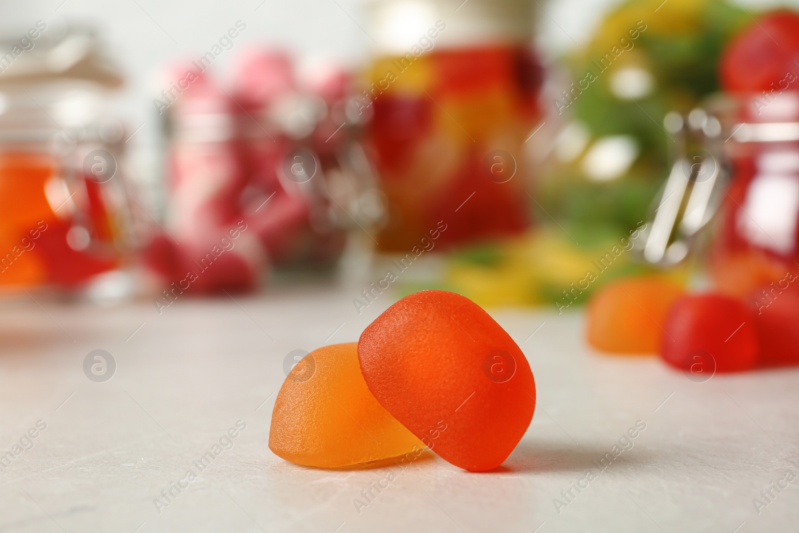 Photo of Tasty orange jelly candies on light table, closeup. Space for text