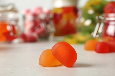 Photo of Tasty orange jelly candies on light table, closeup. Space for text
