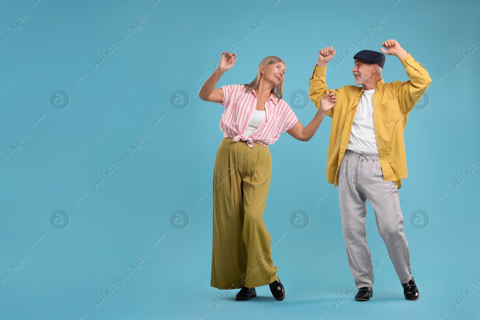 Photo of Senior couple dancing together on light blue background