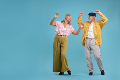 Senior couple dancing together on light blue background