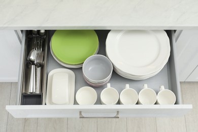 Clean plates, bowls, cups and cutlery in drawer indoors, top view