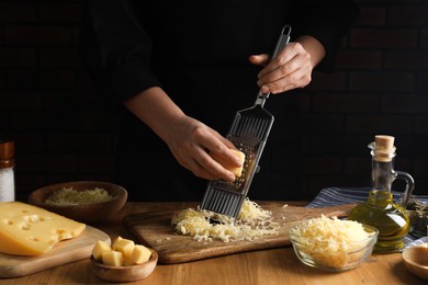 Woman grating cheese at wooden table, closeup