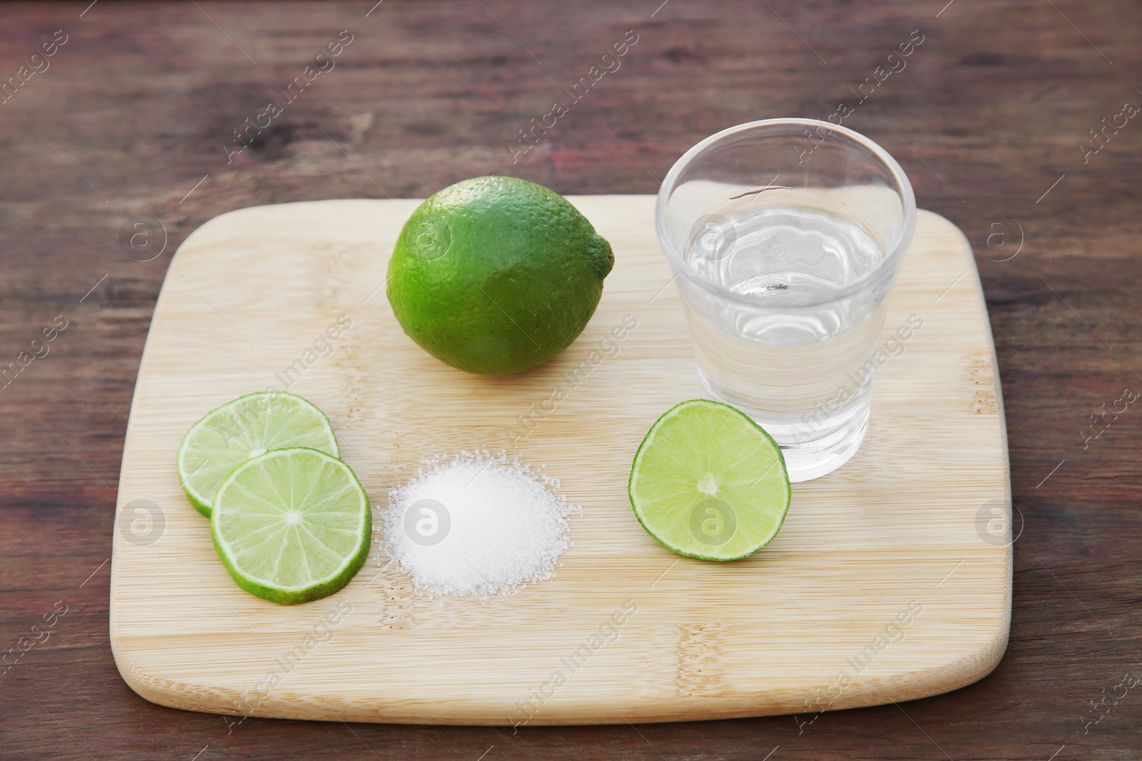 Photo of Mexican tequila shot with lime slices and salt on wooden table. Drink made from agave