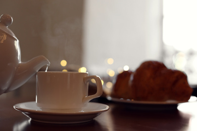 Photo of Delicious morning coffee and croissant served for breakfast on wooden table