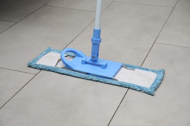 Cleaning grey tiled floor with microfiber mop, closeup