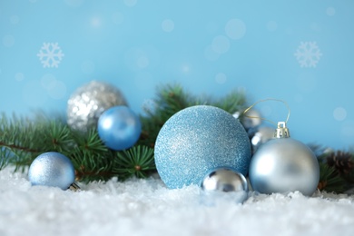 Beautiful Christmas balls and fir tree branch on snow, bokeh effect