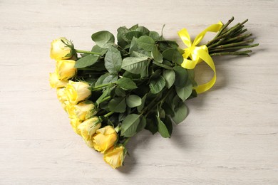 Beautiful bouquet of yellow roses on wooden table, top view