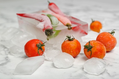 Photo of Frozen vegetables and ice cubes on marble table