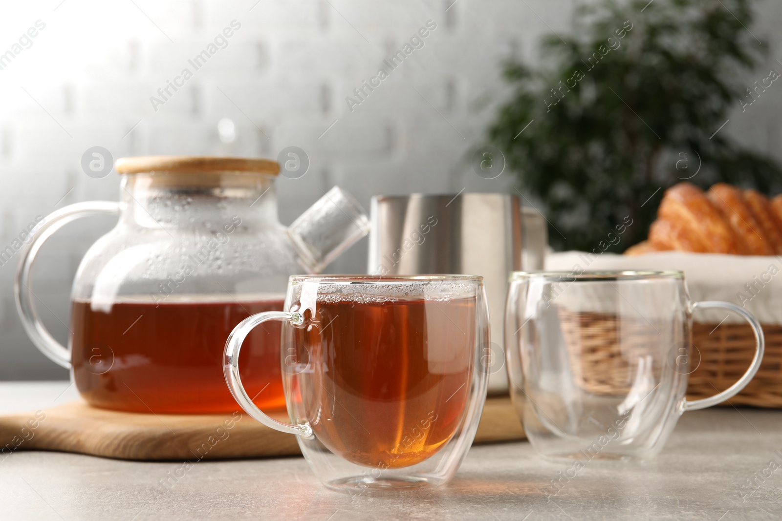 Photo of Aromatic tea in glass cup and teapot on light grey table