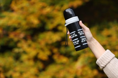 Woman with thermos outdoors, closeup. Space for text