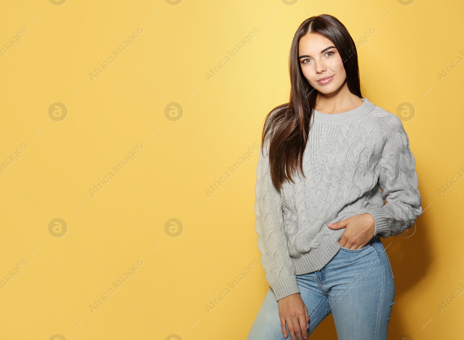 Image of Pretty young woman wearing warm sweater on yellow background. Space for text