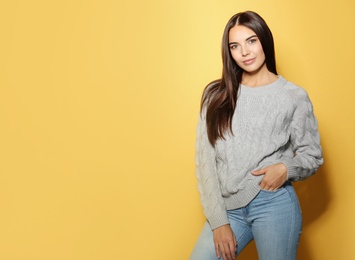 Image of Pretty young woman wearing warm sweater on yellow background. Space for text