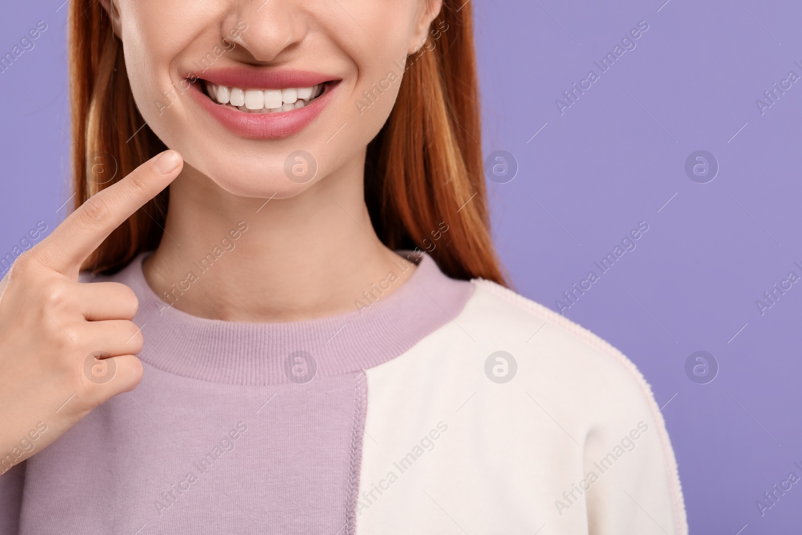 Photo of Woman showing her clean teeth and smiling on violet background, closeup. Space for text