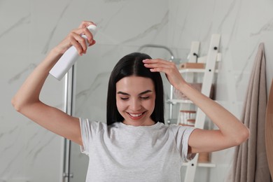 Photo of Woman applying dry shampoo onto her hair in bathroom