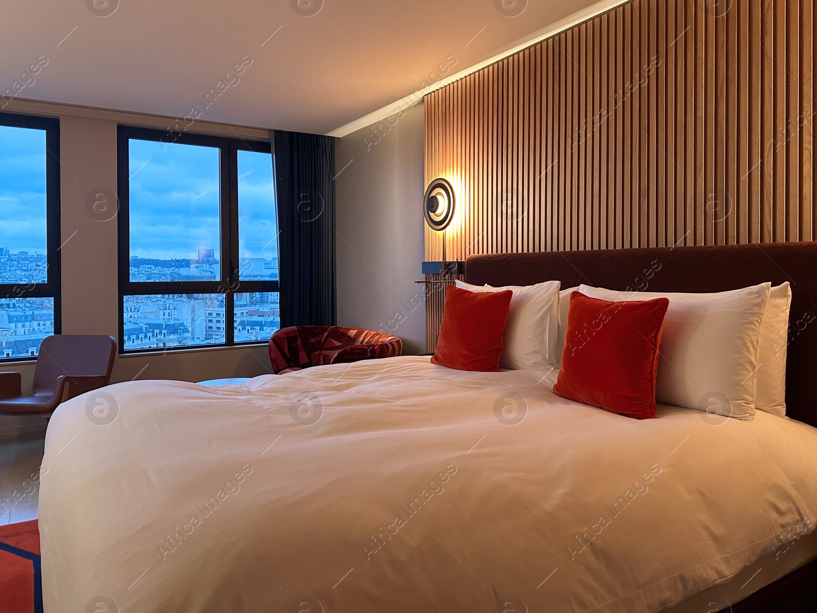 Photo of Stylish hotel room interior with large bed, lamp and chair