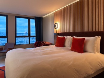 Stylish hotel room interior with large bed, lamp and chair