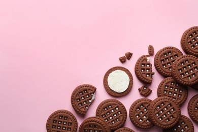 Tasty chocolate sandwich cookies with cream on pink background, flat lay. Space for text