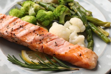 Photo of Healthy meal. Piecegrilled salmon, vegetables, asparagus, lemon and rosemary on plate, closeup