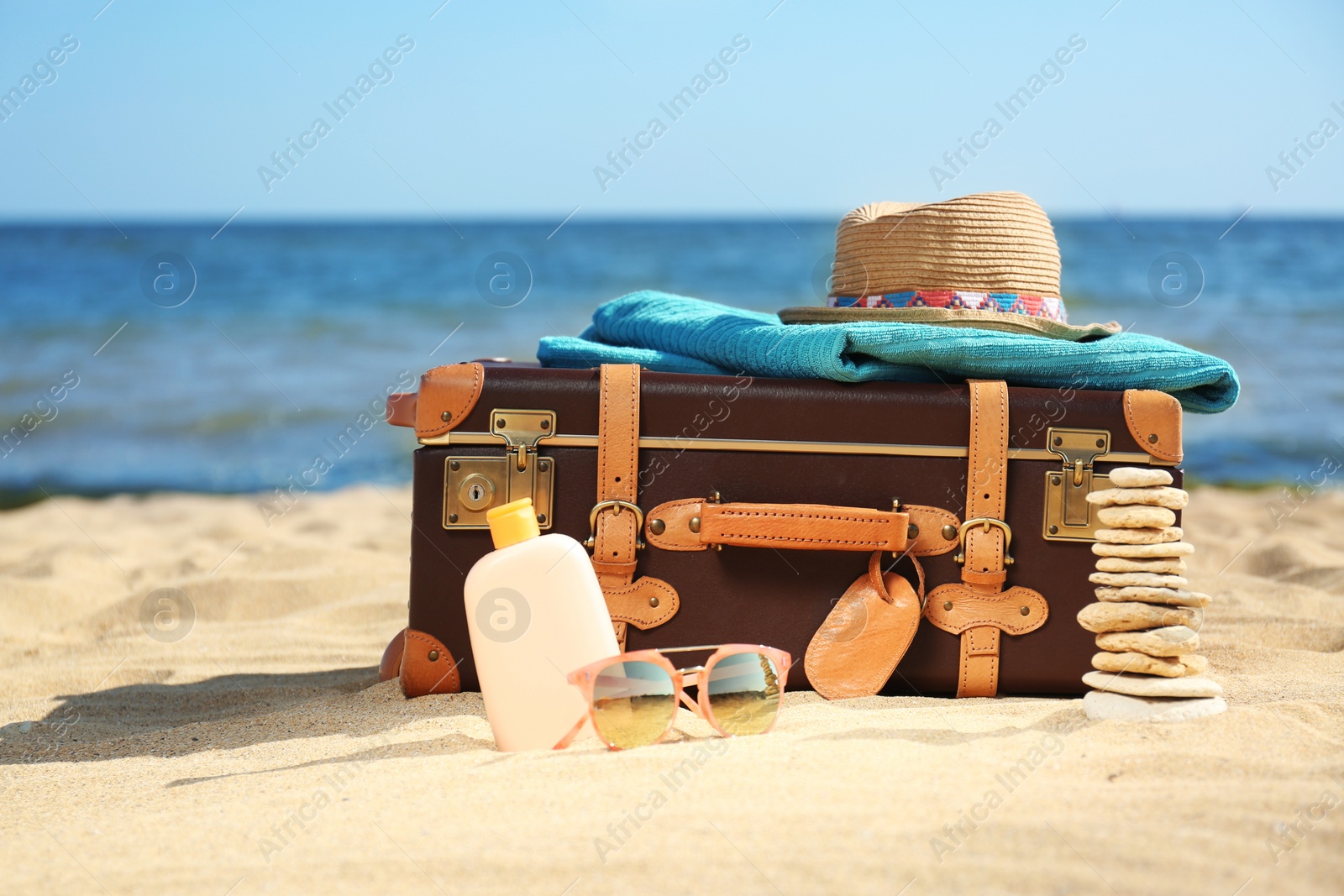 Photo of Suitcase and beach accessories on sand near sea