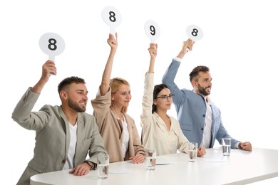 Photo of Panel of judges holding different score signs at table on white background