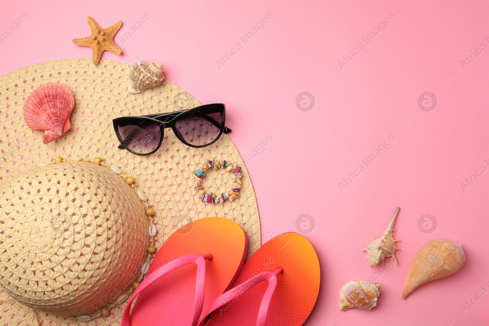 Photo of Flat lay composition with beach accessories on pink background. Space for text