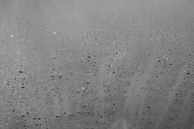 Photo of Glass with rain drops against light background