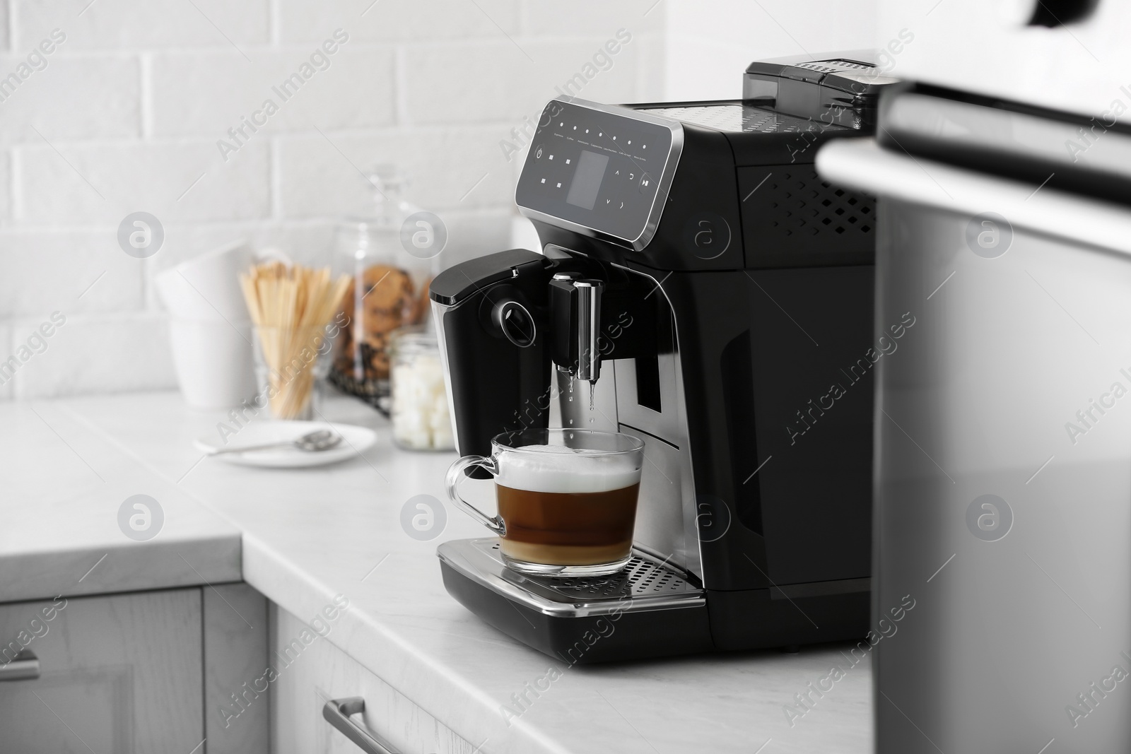 Photo of Modern electric espresso machine making coffee with milk on white marble countertop in kitchen