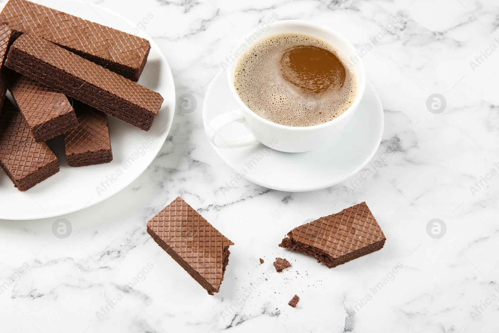 Photo of Plate of delicious chocolate wafers with cup of coffee on marble background