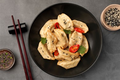 Photo of Delicious gyoza (asian dumplings) served on gray table, flat lay