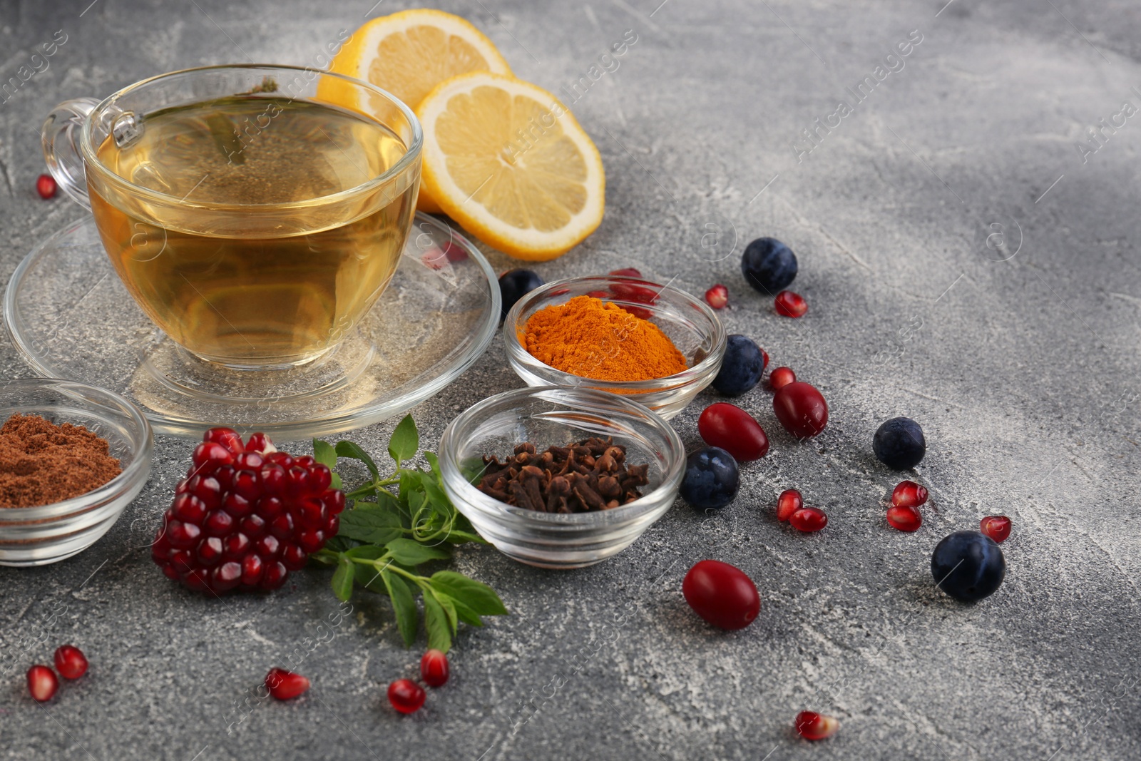 Photo of Cup with delicious immunity boosting tea and ingredients on grey table