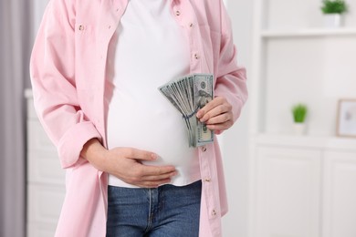 Surrogate mother. Pregnant woman with dollar banknotes indoors, closeup. Space for text