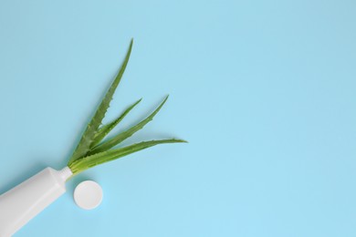 Photo of Tube of toothpaste and fresh aloe on light blue background, flat lay. Space for text