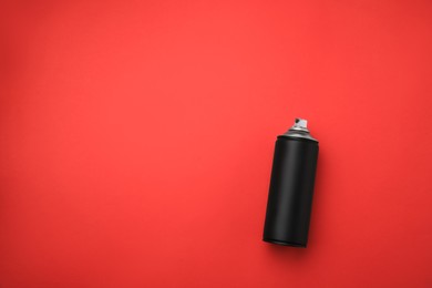 Can of black graffiti spray paint on red background, top view. Space for text