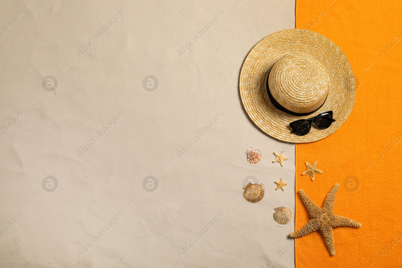 Photo of Beach towel, hat, sunglasses, starfishes and seashells on sand, flat lay. Space for text