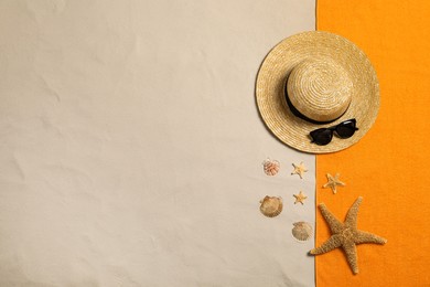 Beach towel, hat, sunglasses, starfishes and seashells on sand, flat lay. Space for text